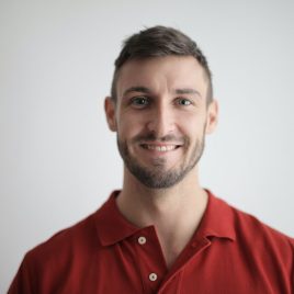 a man in a red shirt smiling at the camera.