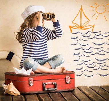 a little girl sitting on a suitcase looking through a pair of binoculars.