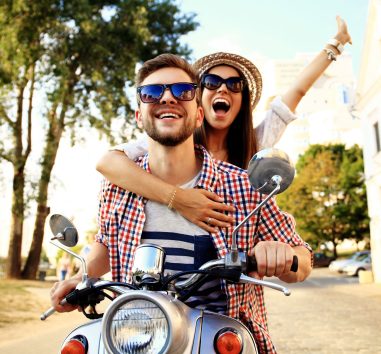a man and a woman riding on the back of a scooter.